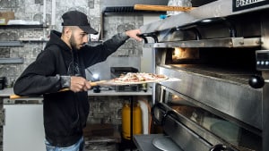 Nour Mamura i gang ved ovnen i pizzeria Pizzamester i Agerbæk. Agerbæk havde ét pizzeria i forvejen - nu har byen to. Foto: Chresten Bergh