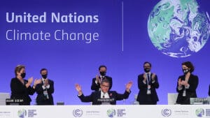 COP26-formand Alok Sharma rækker hænderne ud, mens han modtager bifald ved afslutningen af klimamødet i Glasgow lørdag aften. Han siger selv, at han ville ønske, at han havde kunnet bevare den oprindelige, skrappere tekst om udfasning af kulkraft - i stedet for nedtrapning, som teksten endte med at nævne. Foto: Yves Herman/Reuters