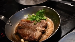 En T-bone-steak kræver en god pande, her er det 363 gram færdigmodnet bøf fra Dagli'brugsen. Jernpanden giver fin stegeskorpe, og man kan, som køkkenchef Steffen Falkesgaard Hansen foreslår det i podcasten 