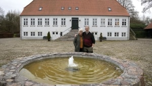 Helle og Peter Juhl på gårdspladsen, hvor den gamle  brønd er omdannet til et springvand. I gamle dage så brønden ud som dem, man kan se inde i Christiansfeld, men det er i dag taget af tidens tand. Foto: Søren Gylling