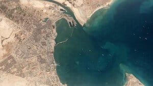Helt oppe i venstre hjørne kan man på satellitfotoet se det 400 meter lange grundstødte containerskib ligge på tværs i den smalle Suez-kanal. I bassinet foran venter mange skibe på passage. Foto: Planet Labs Inc/Reuters
