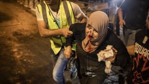 En redningsarbejder hjælper en såret kvinde væk under uroligheder i Sheikh Jarrah-kvarteret i Jerusalem lørdag aften. Foto: Ilia Yefimovich/Ritzau Scanpix