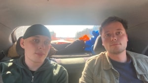 Mads-Emil Longhi sidder sammen med journalist Emil Jørgensen på bagsædet af hans bil. De er på vej til Danmark. Foto: Lasse Sandborg